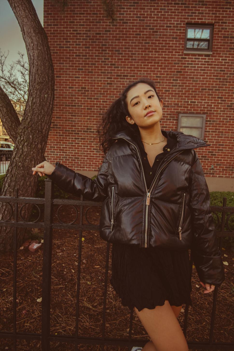 Free Image of Chic woman leaning on black fence 
