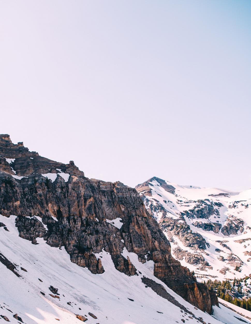 Free Image of Rocky cliffs with snow under blue sky 