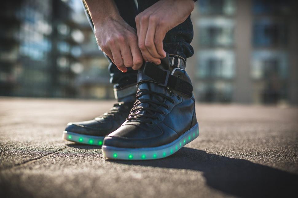 Free Image of Man tying LED light-up shoes on street 
