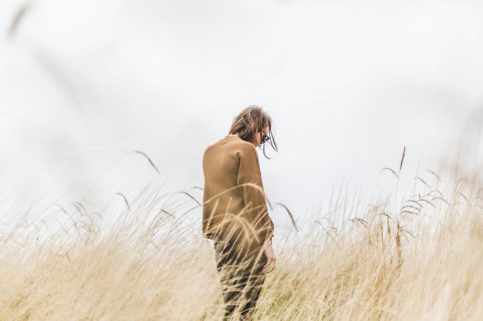 Free Image of Woman standing amidst tall dry grass 