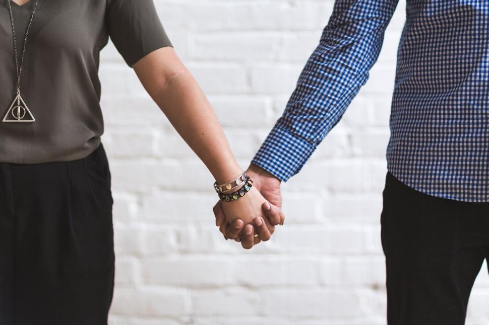 Free Image of Couple holding hands with hidden faces 