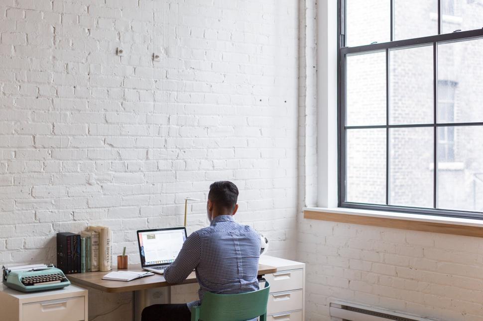 Free Image of Man working at a desk with a computer in a room 