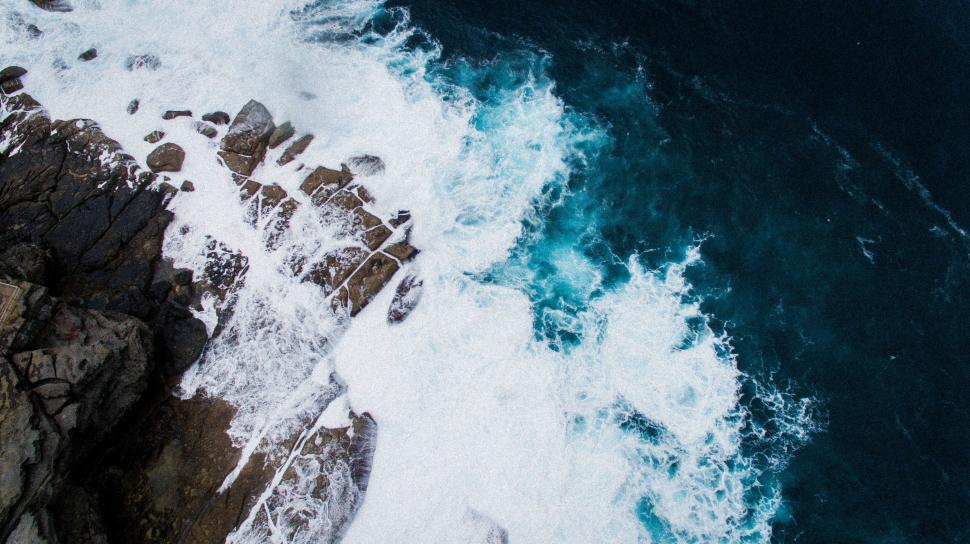 Free Image of Aerial view of waves crashing on rocks 