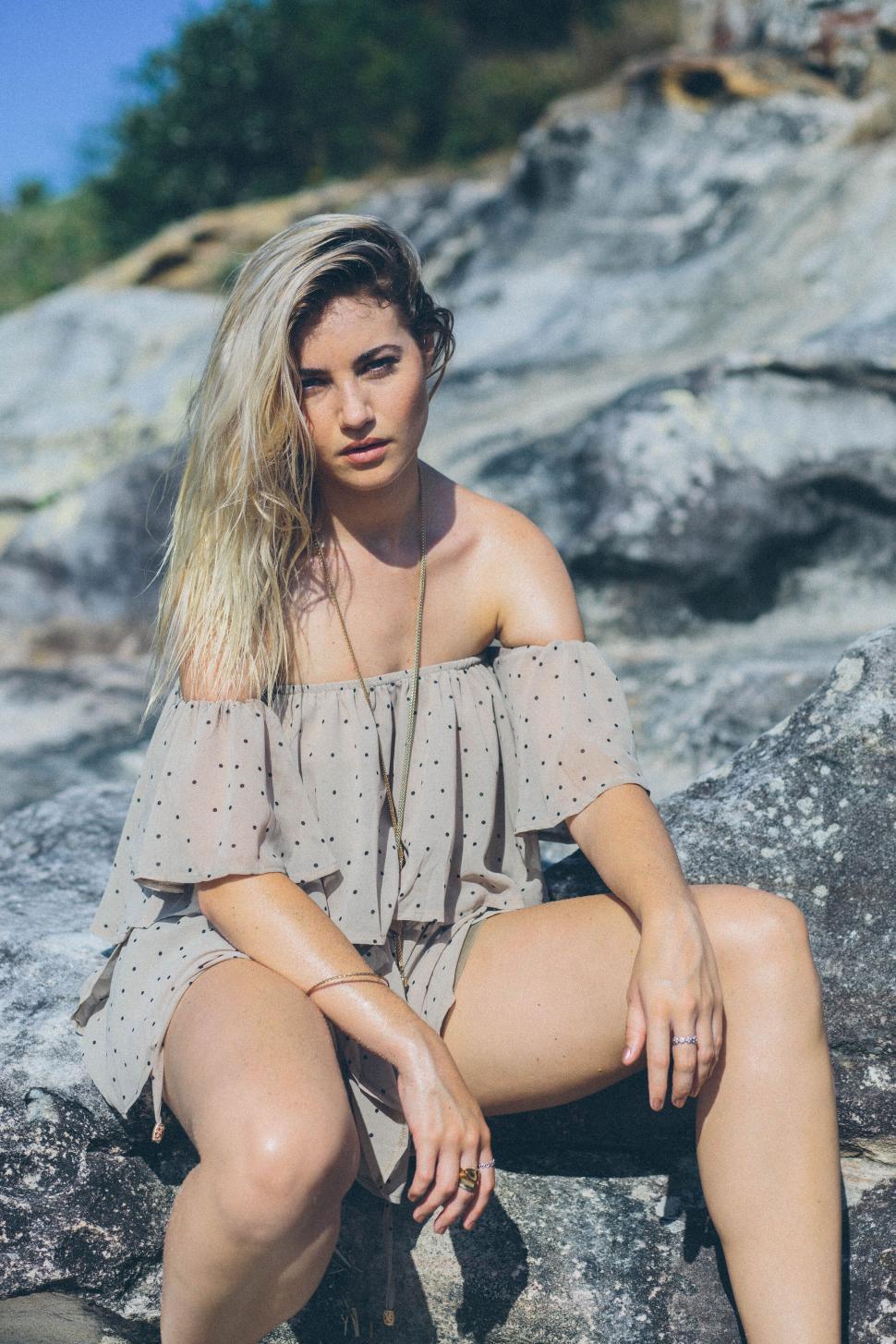 Free Image of Woman relaxing on a rocky beach 