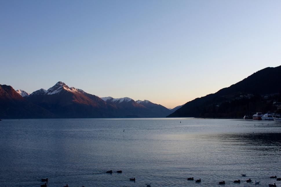 Free Image of Tranquil lake scene with mountains at dusk 