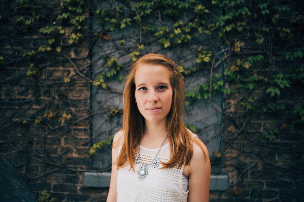 Free Image of Young woman posing before ivy-covered wall 