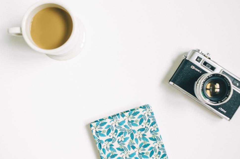 Free Image of Vintage camera beside floral notebook and coffee 