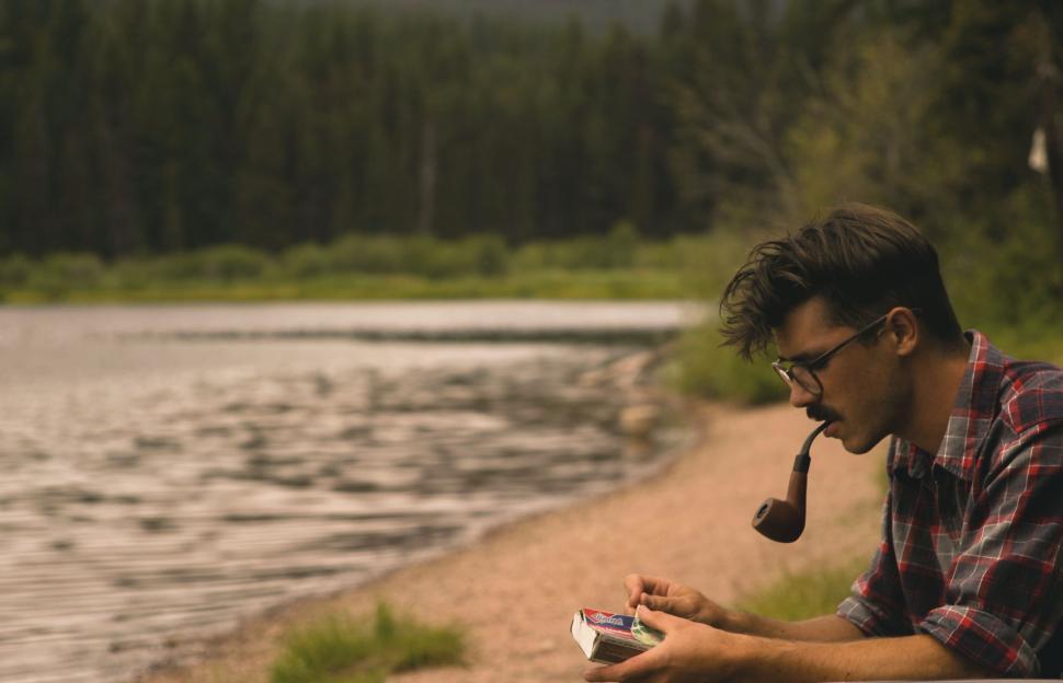 Free Image of Man with blurred face by the lake with pipe 