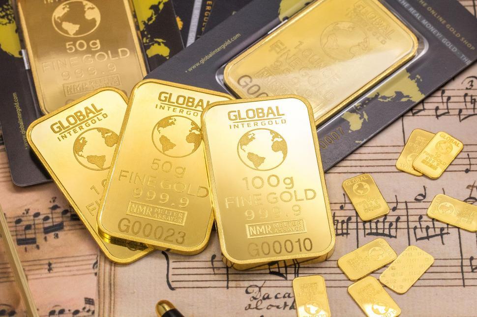 Free Image of Stacks of gold bars over financial documents 