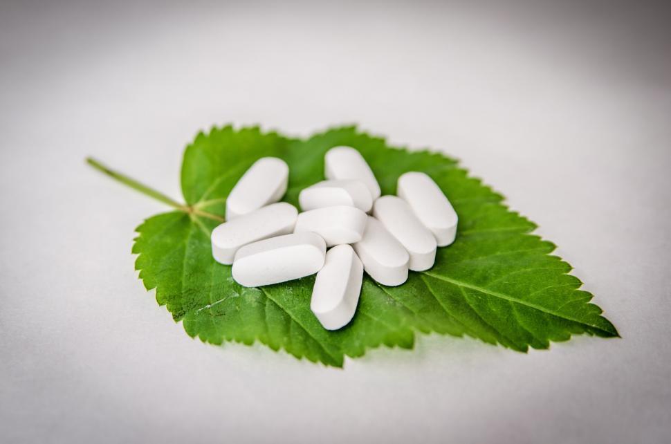 Free Image of White pills on a green leaf with dew 