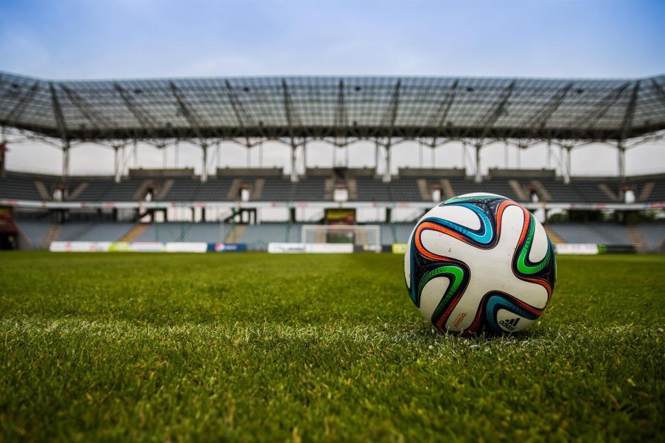 Free Image of Soccer ball on a grass field with stadium 
