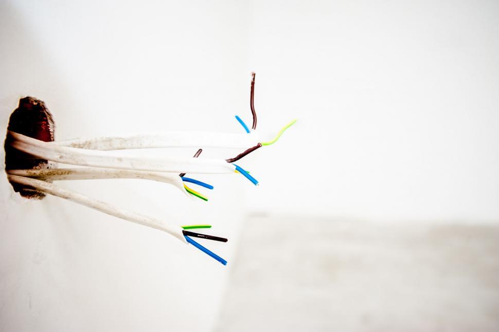 Free Image of Exposed electrical wires in a white wall 