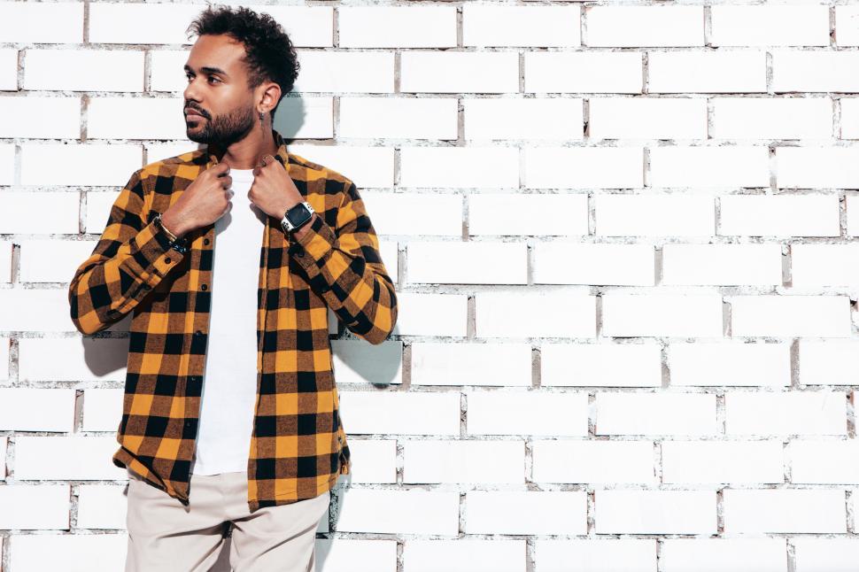 Free Image of A man standing against a white brick wall 