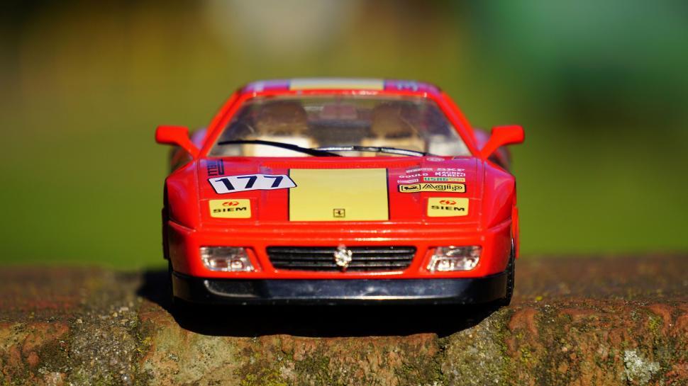 Free Image of Red toy Ferrari model on a brick surface 