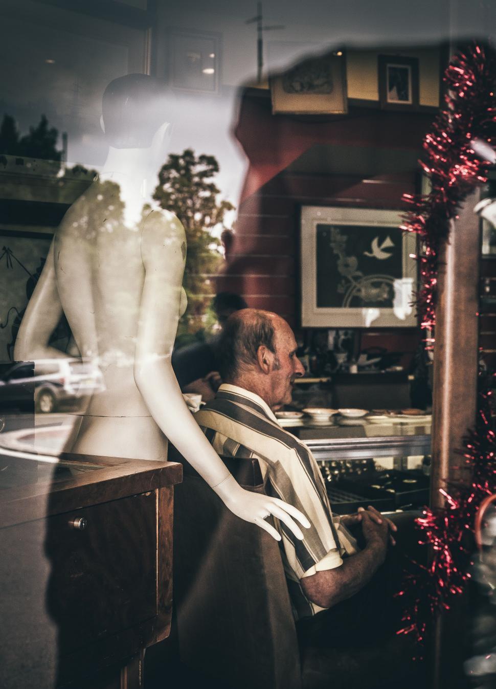 Free Image of Mannequin and blurred figure through glass 