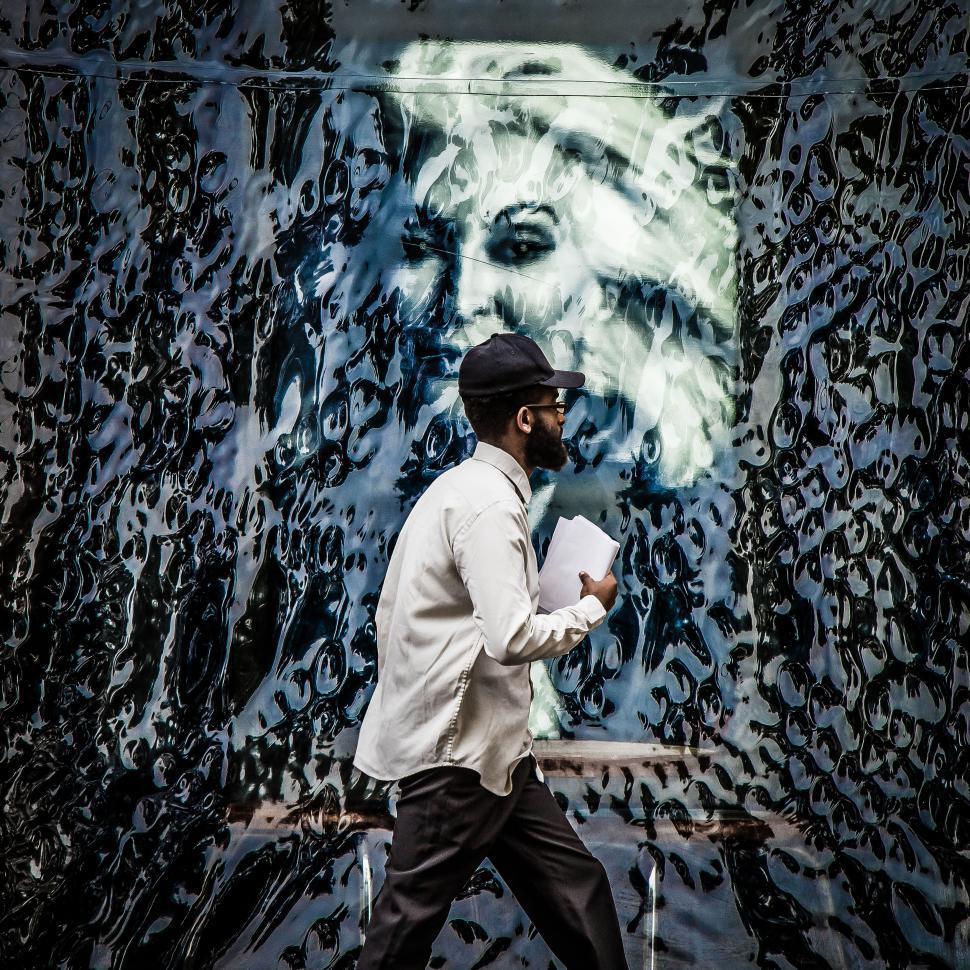 Free Image of Man walking past an artistic mural 