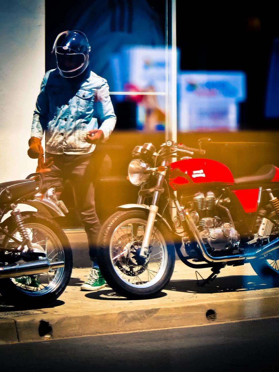 Free Image of Biker with helmet standing next to a motorcycle 