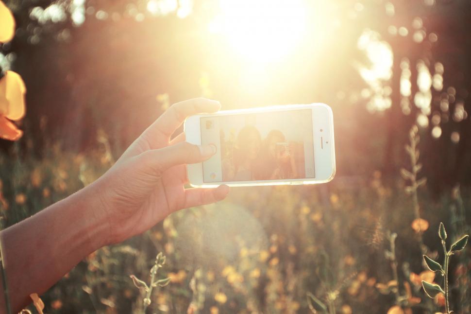 Free Image of Hand holding smartphone capturing sunset 