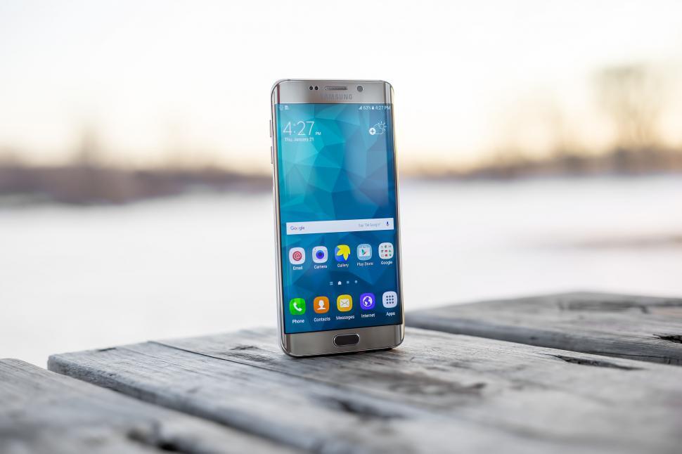 Free Image of Smartphone with scenic wallpaper on wooden dock 