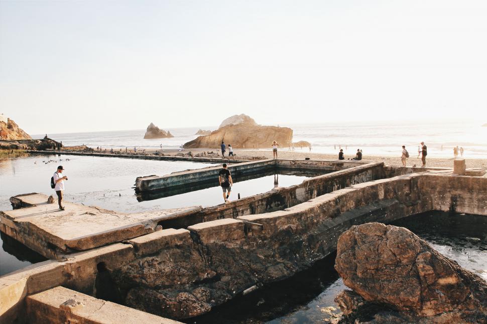 Free Image of People at a coastal tidal pool during sunset 