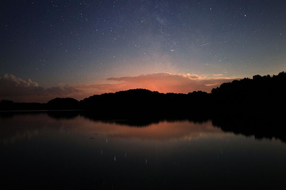 Free Image of Starry night sky reflecting on a calm lake 