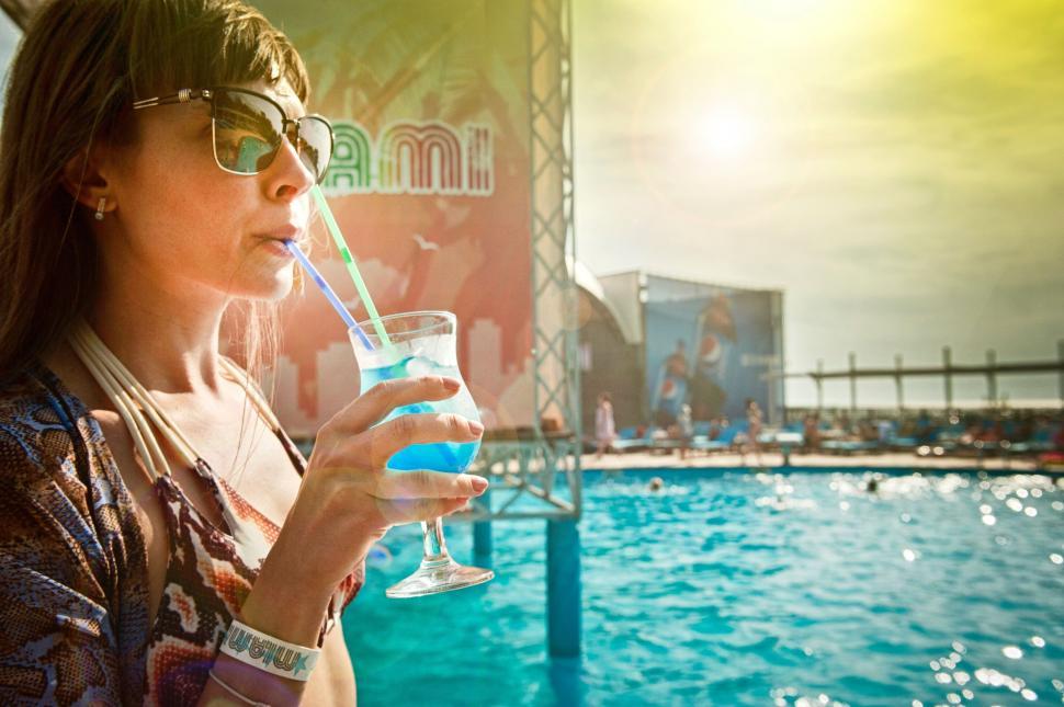 Free Image of Woman holding a blue drink with blurred backdrop 
