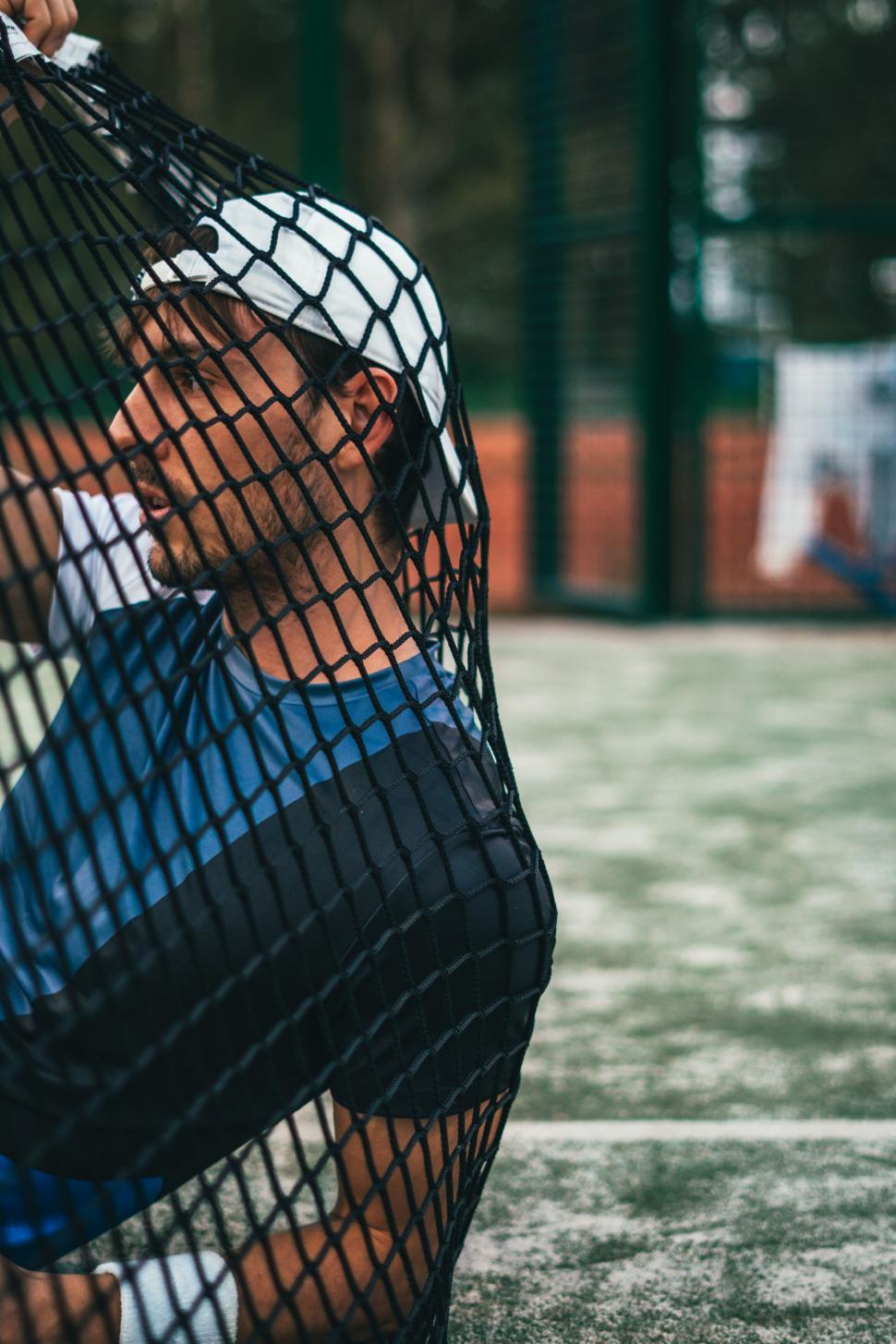 Free Image of Man resting behind a soccer goal net 