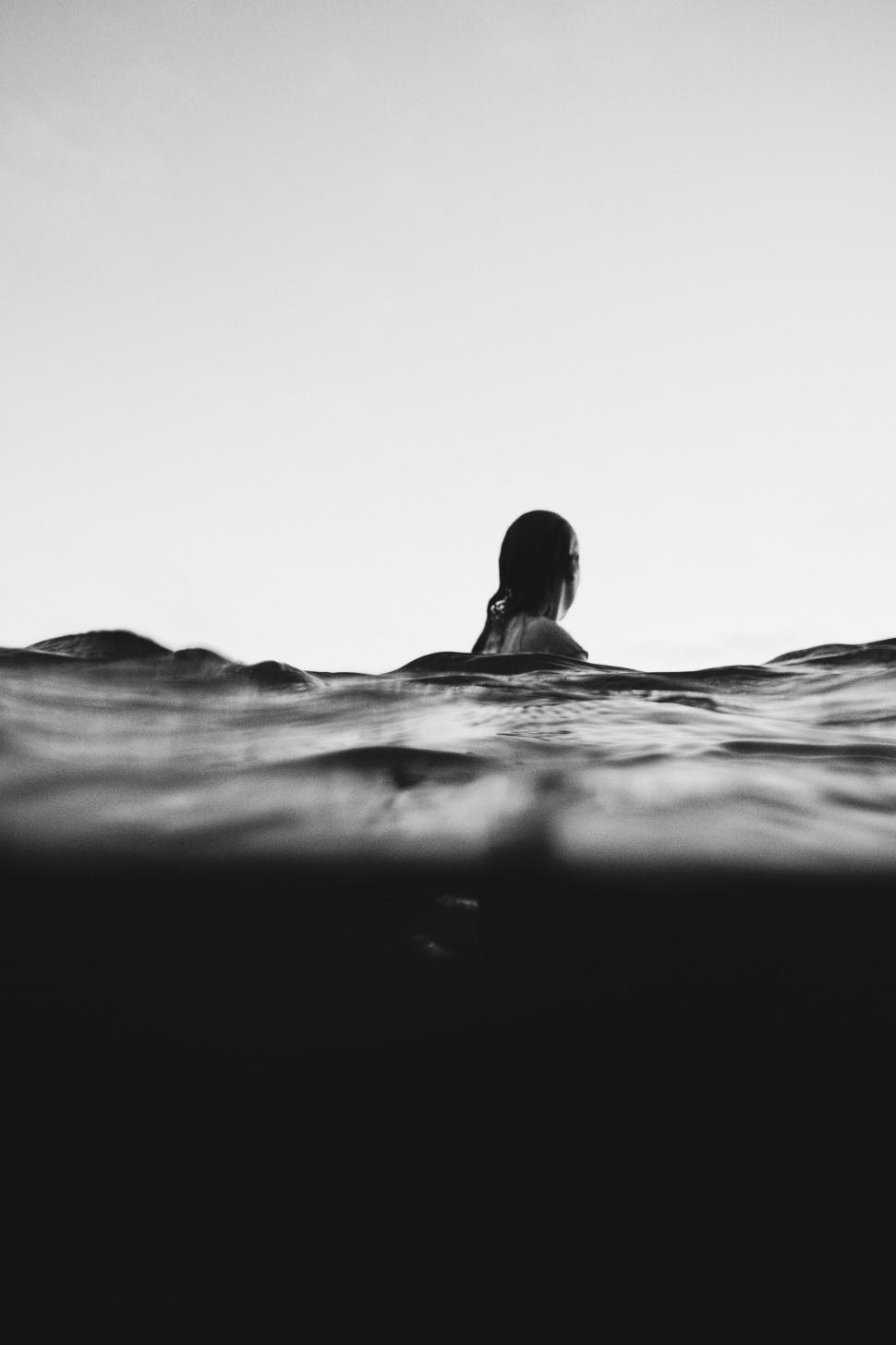 Free Image of Person swimming in the ocean at dusk 