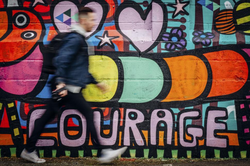 Free Image of Blurry figure running past street mural 
