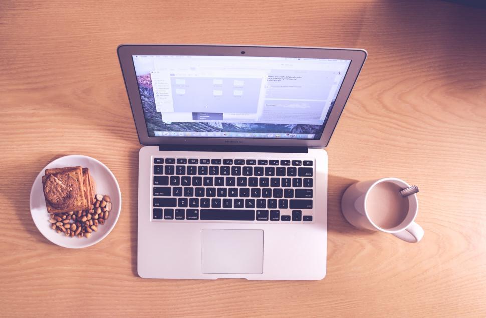 Free Image of Laptop, cake, and cup on wooden desk 