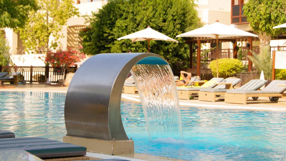 Free Image of Sunlit pool with a metal water feature 