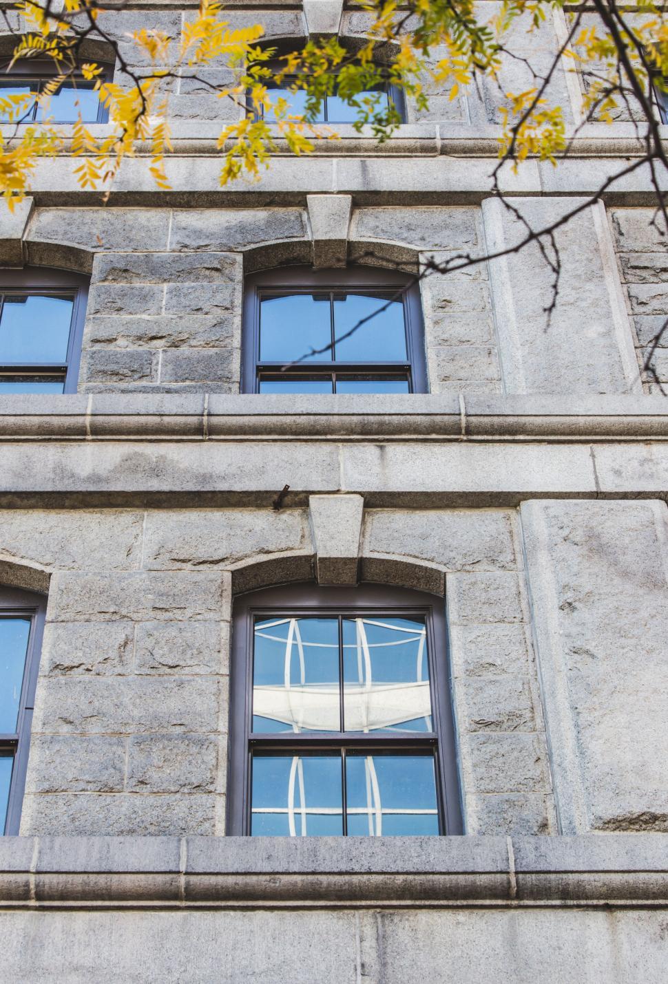 Free Image of Reflection in window of stone building 