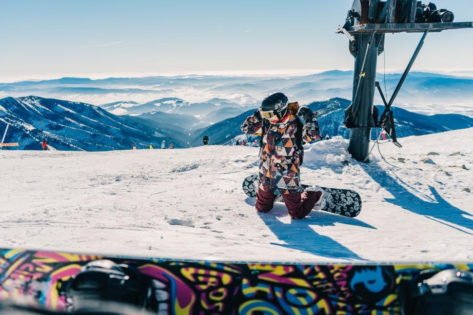 Free Image of Snowboarder adjusting equipment on slope 