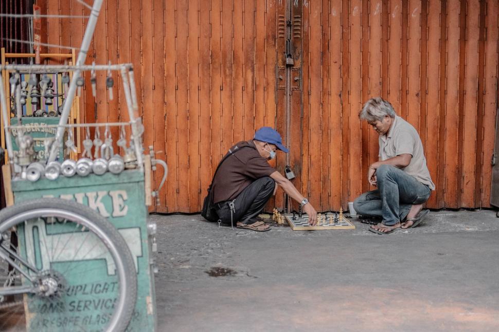 Free Image of Two men playing chess on the sidewalk 
