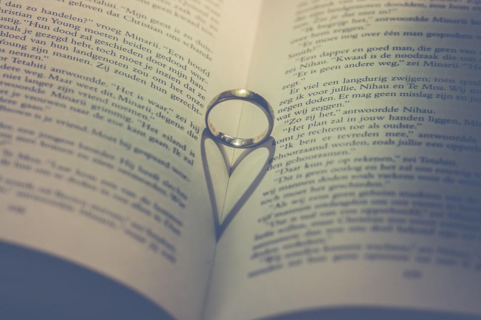 Free Image of Wedding ring casting heart shadow on book 