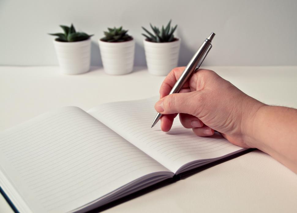 Free Image of Writing hand on a blank notebook with plants 