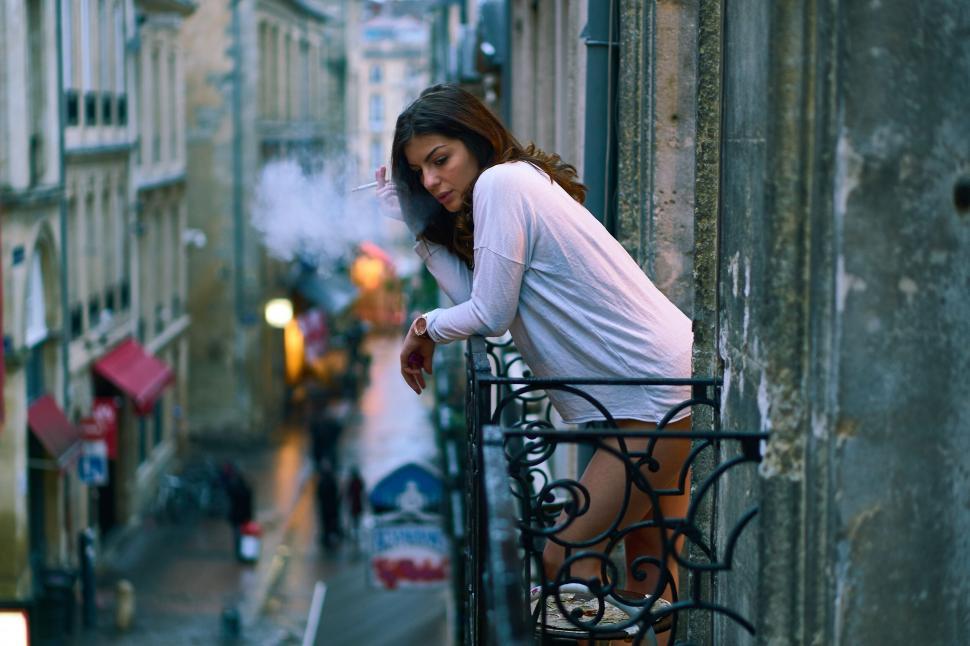 Free Image of Woman leaning on balcony railing 