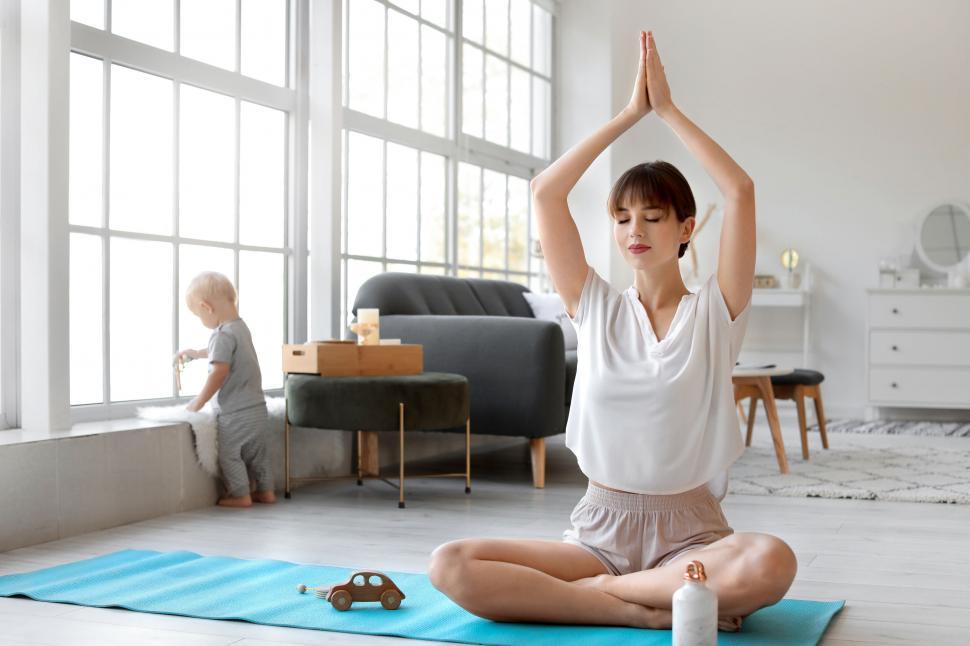 Free Image of Woman in meditation with child in the background 