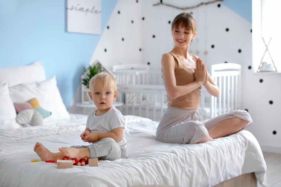 Free Image of Mother and smiling child on bed in yoga session 