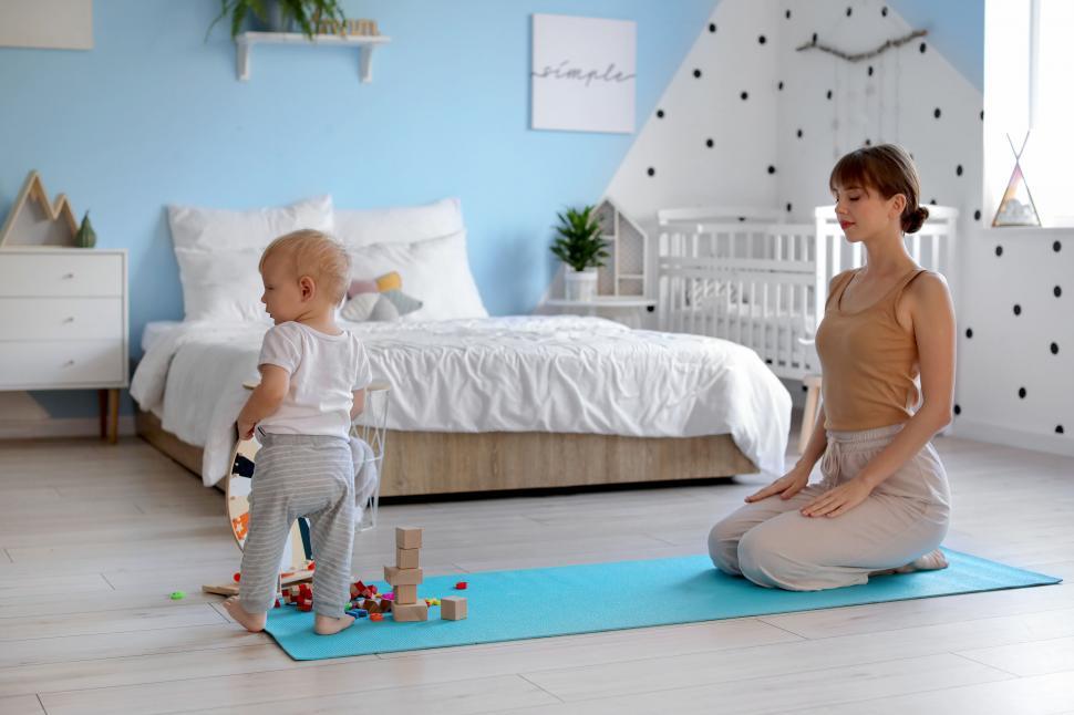 Free Image of Mother centered in yoga pose with playful child 