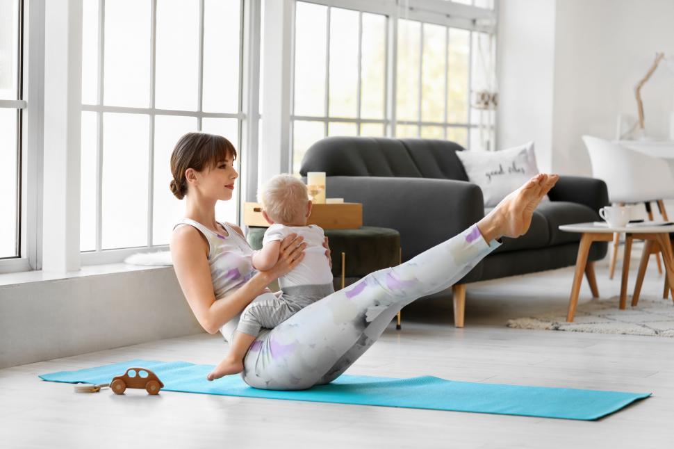 Free Image of Mother doing boat pose yoga with a toddler 