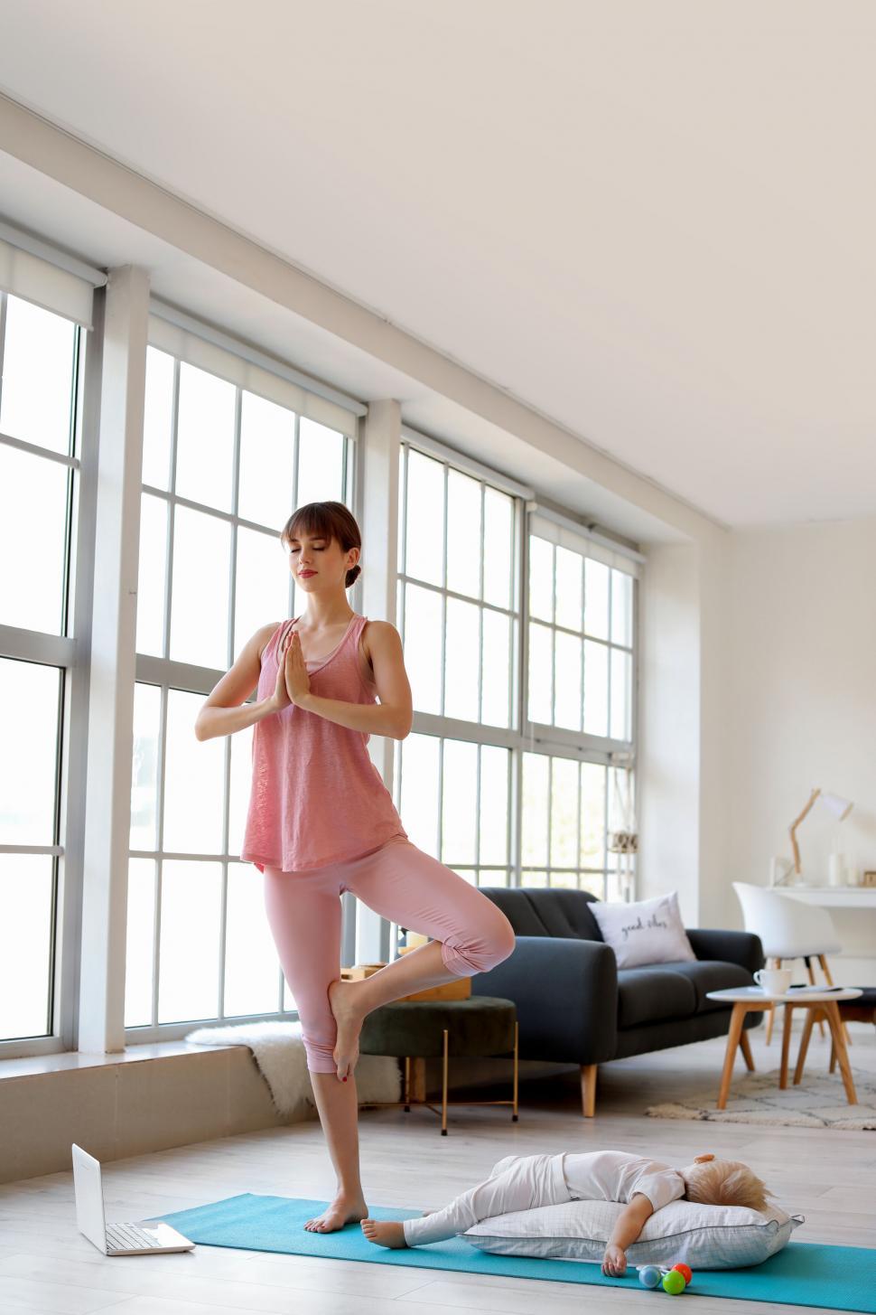 Free Image of Mother balances on one leg in yoga pose with child 