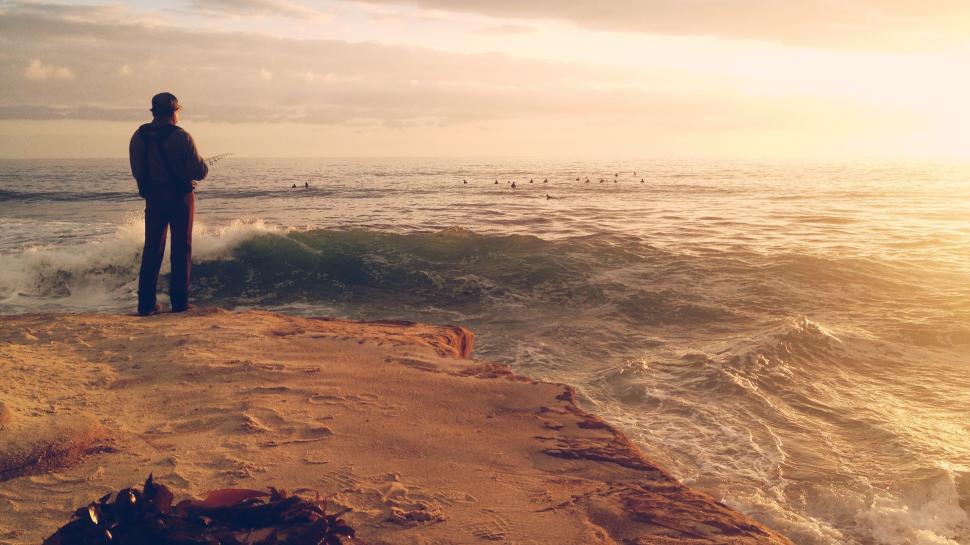 Free Image of Man observing surfers at sunset 