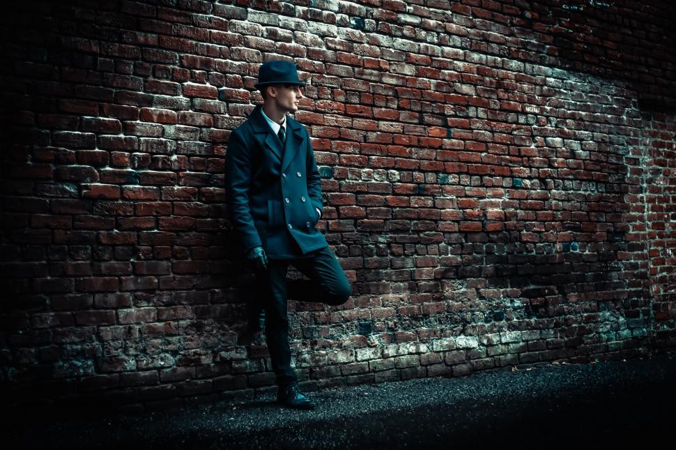 Free Image of Man leaning against brick wall in suit 