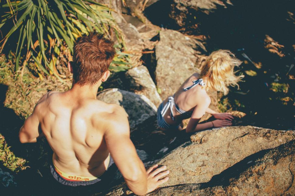 Free Image of Young couple relaxing by rocky shore 