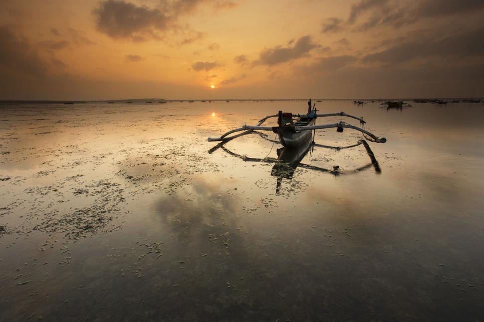 Free Image of Traditional fishing boat on calm waters at sunrise 