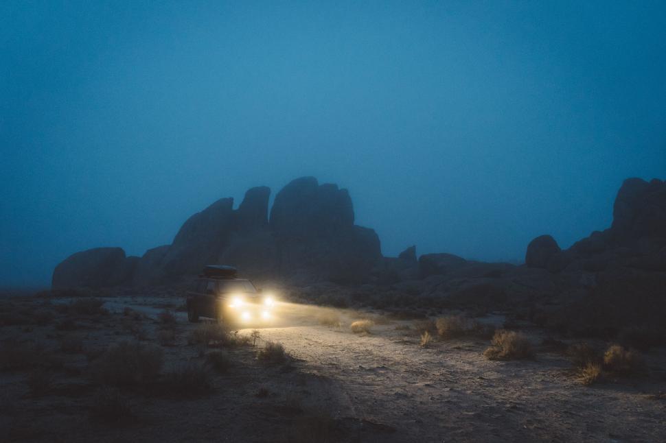 Free Image of Vehicle headlights illuminating foggy desert 