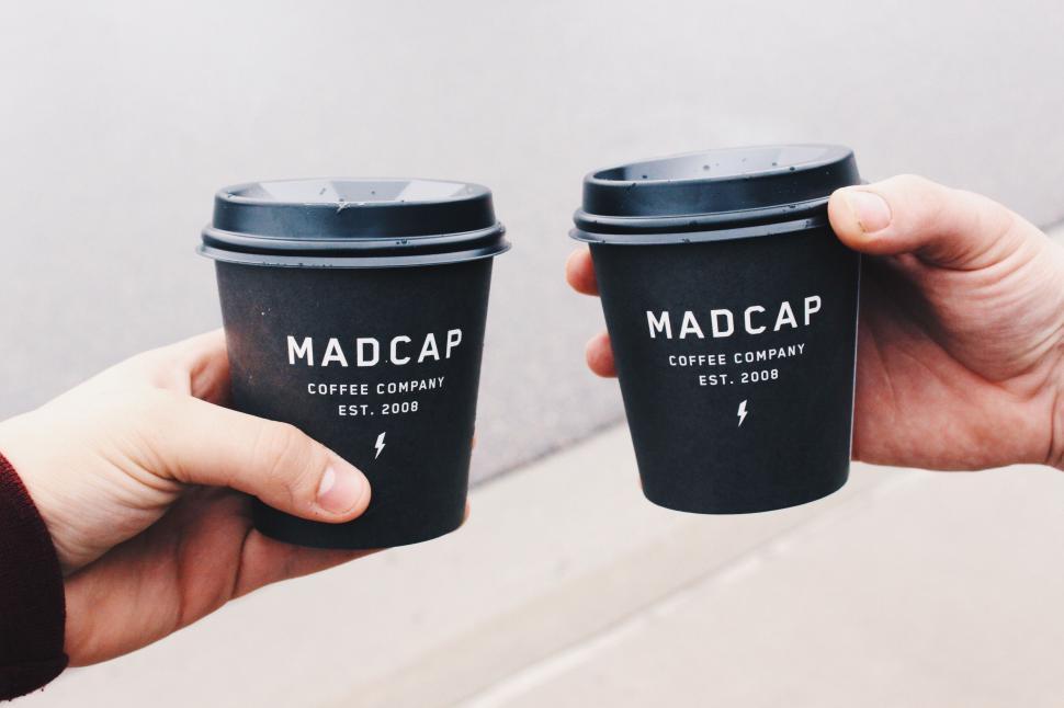 Free Image of Two hands holding branded coffee cups 