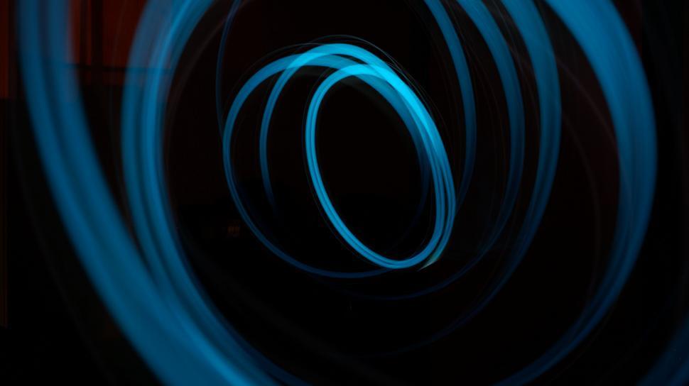 Free Image of Blue light trails in a circular motion on black 