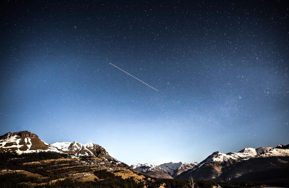 Free Image of Starry night sky over snow-covered mountains 